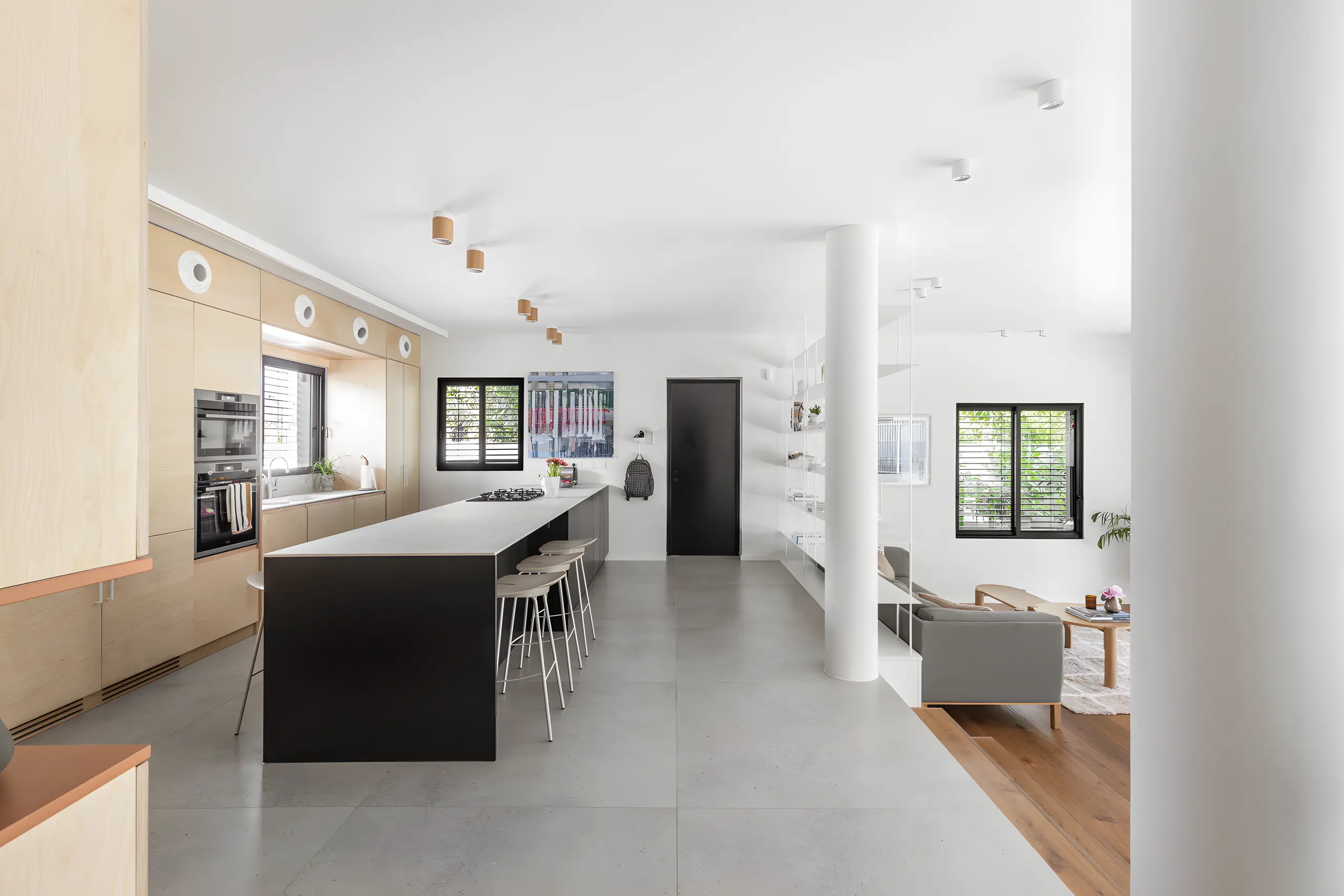 Black kitchen island against pale grey floor tiles with the garden beyond