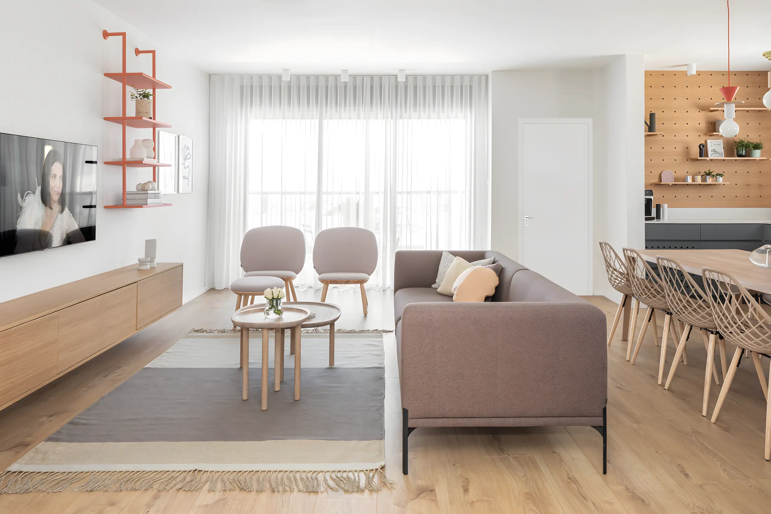 Living room with a mauve sofa, pale chairs and coral shelving on a light oak floor