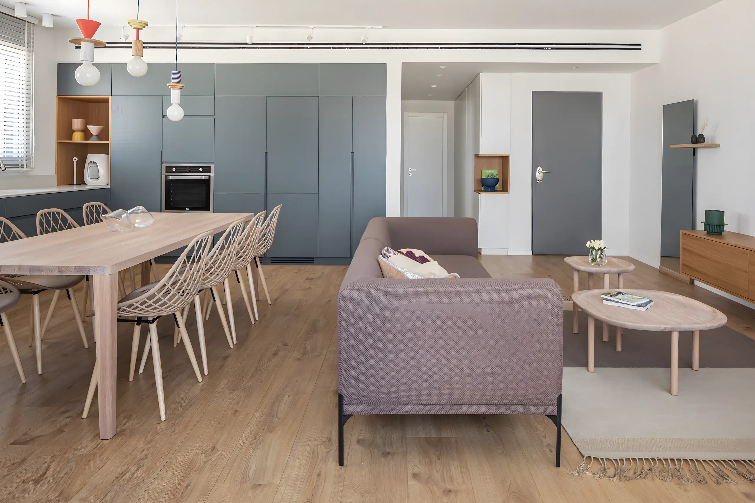 Dining table and chairs with the dark grey kitchen and the living room beyond