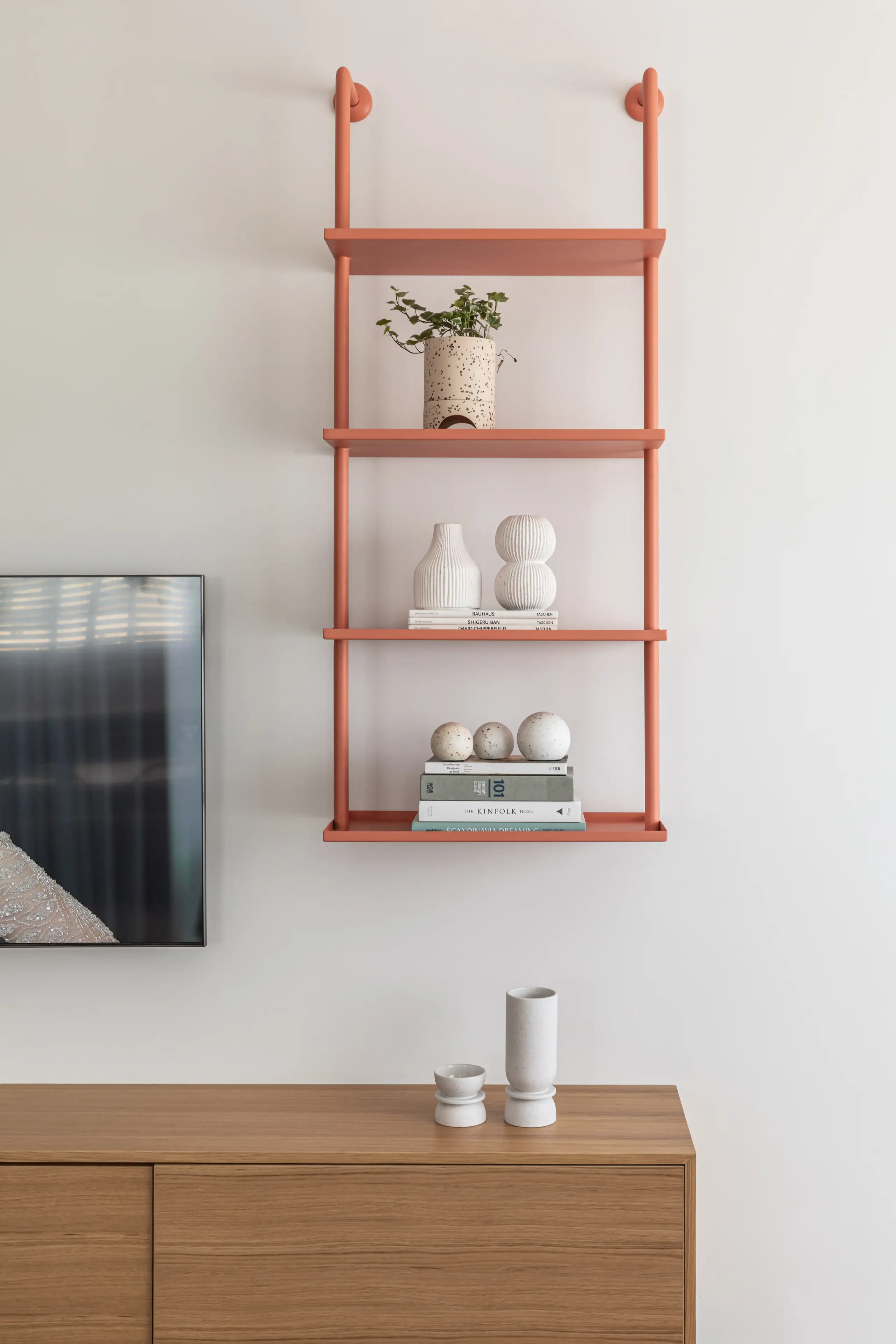 Coral open shelving with white vases against a white wall