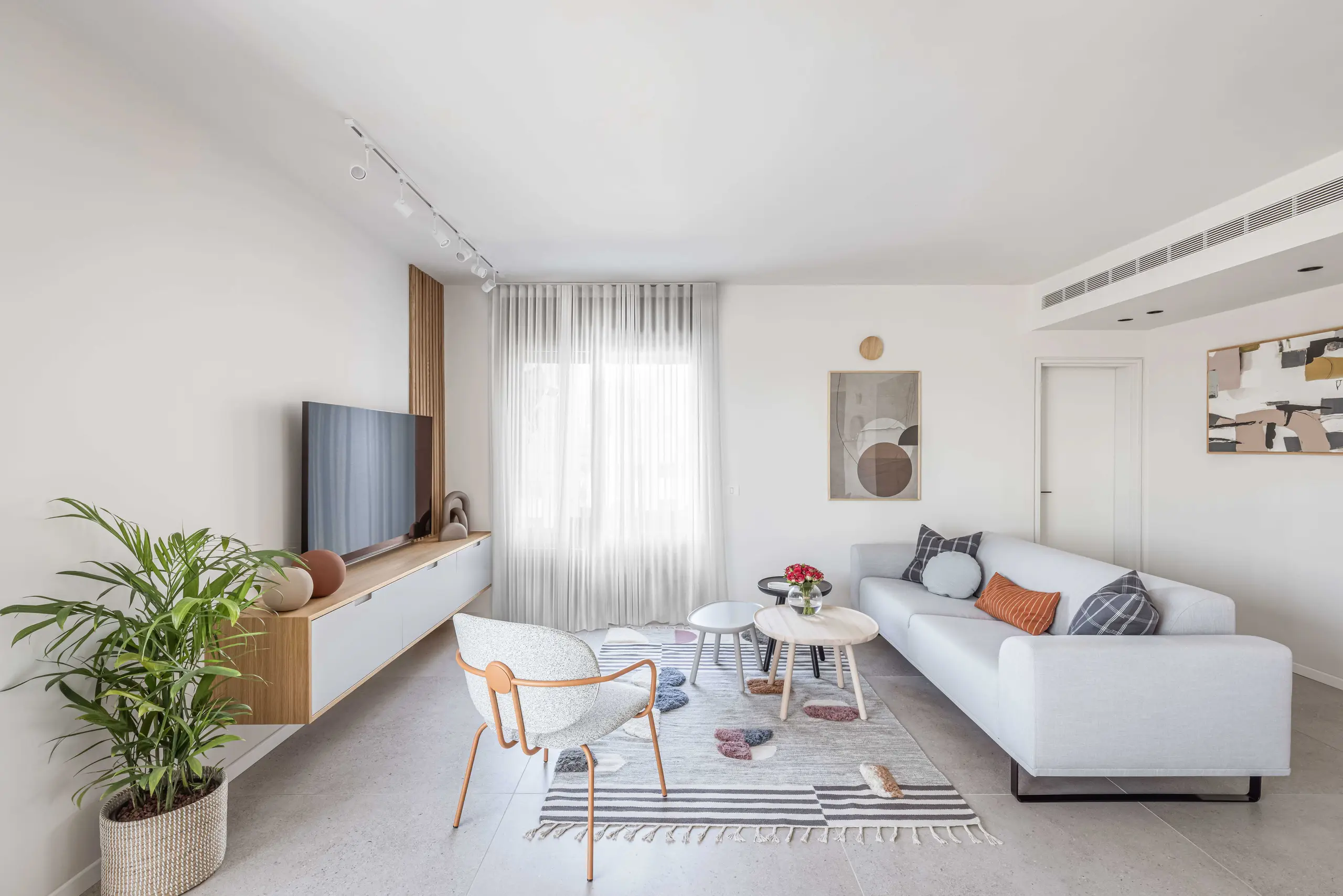 Living room with a long low oak cabinet under the window, a white sofa and a sheer curtain