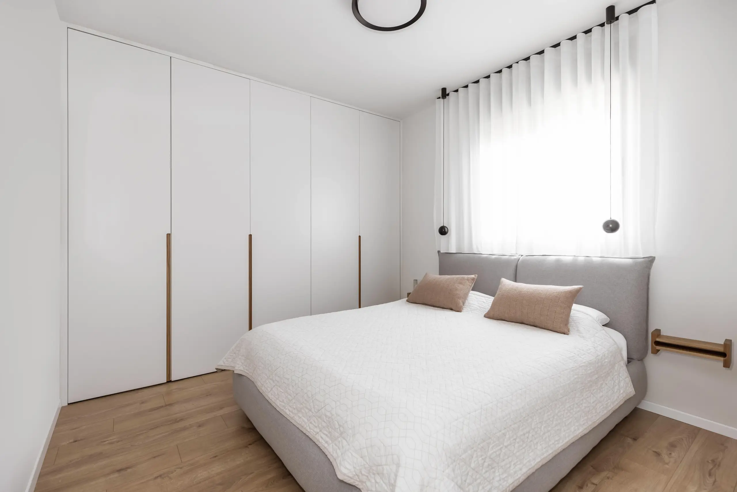 Bedroom with wall-to-wall white wardrobes and an oak floor