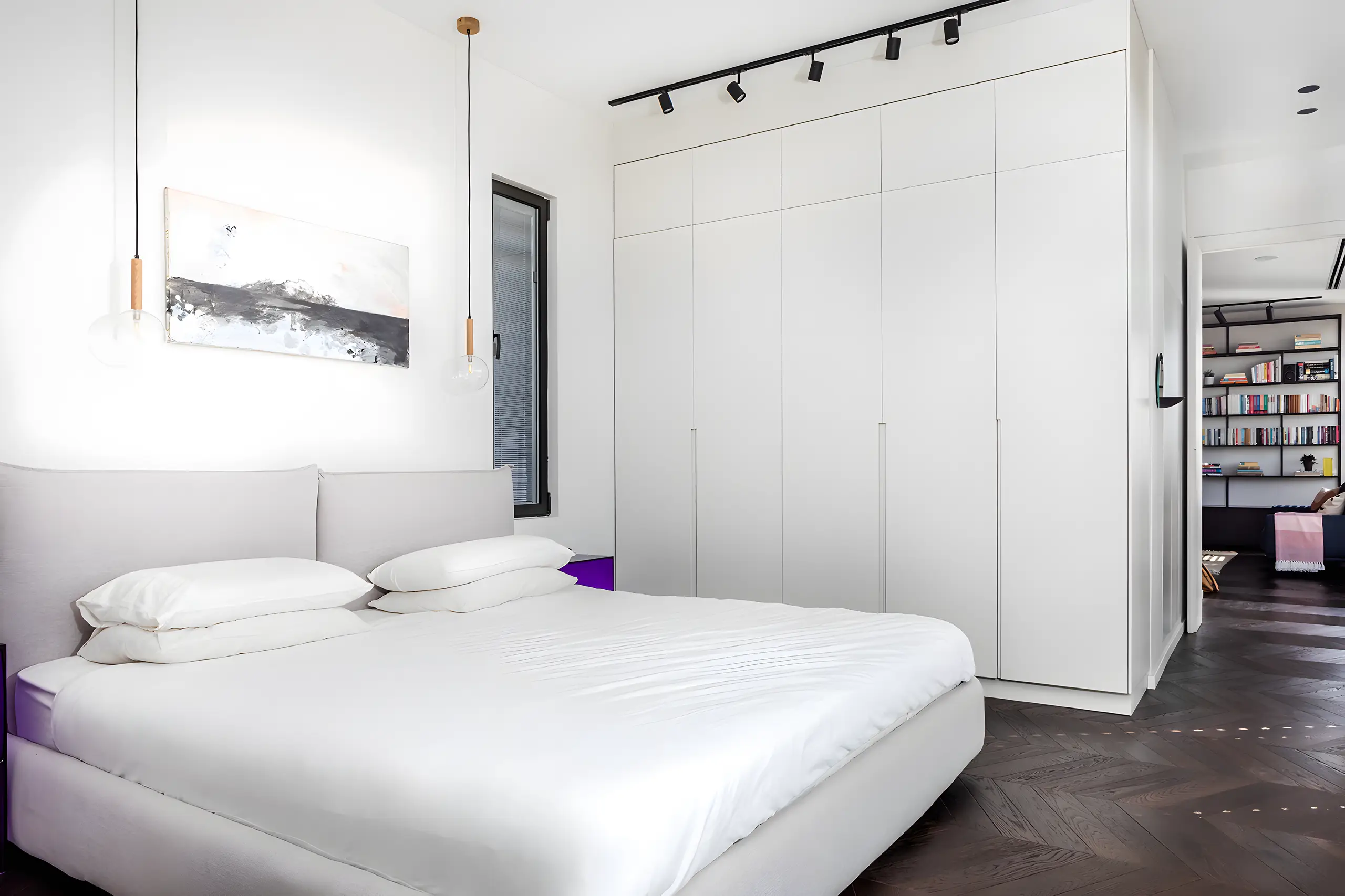 White bedroom with built-in wardrobes and a dark parquet floor