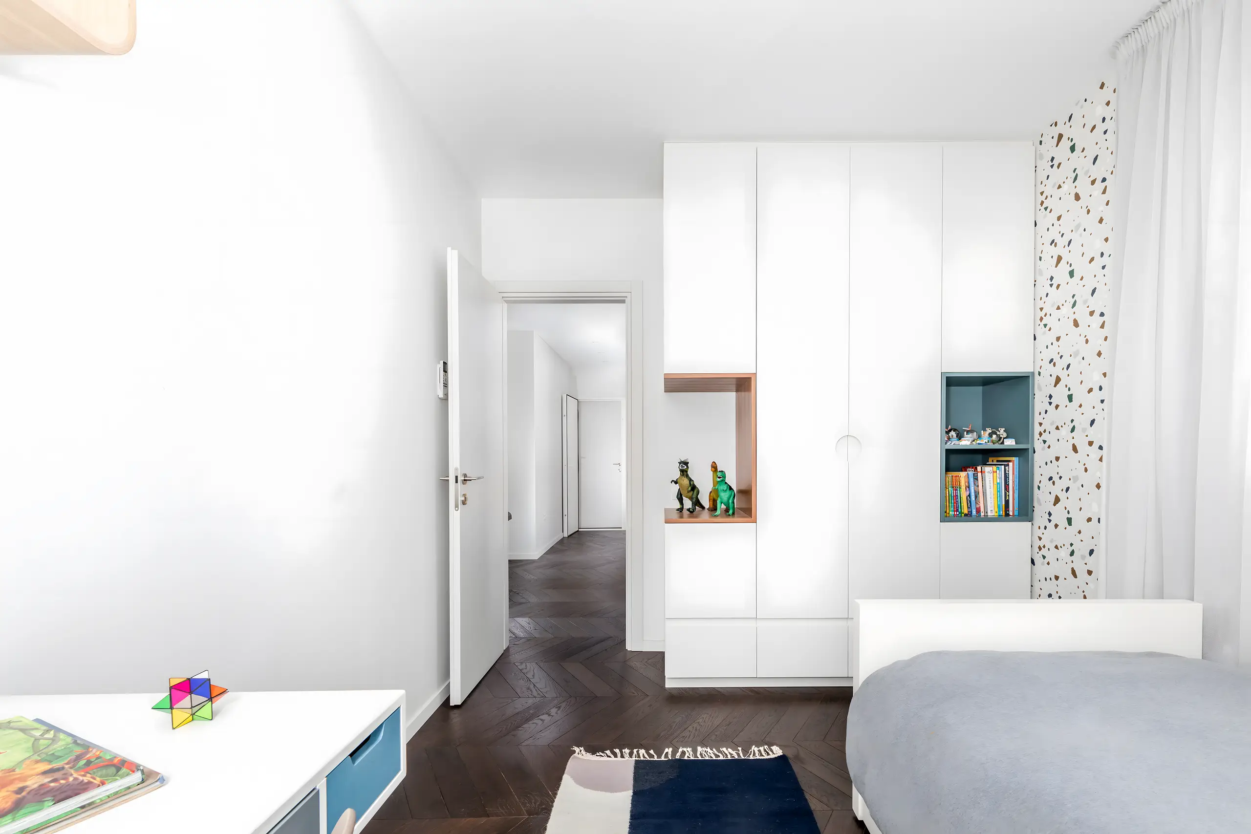 Corridor to the bedrooms with white built-in storage and a dark parquet floor