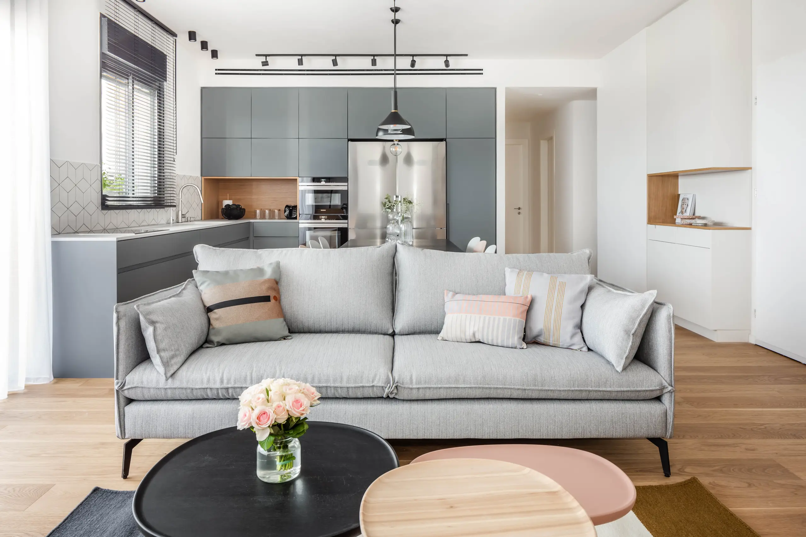 Grey kitchen and grey sofa with black round tables on an oak floor