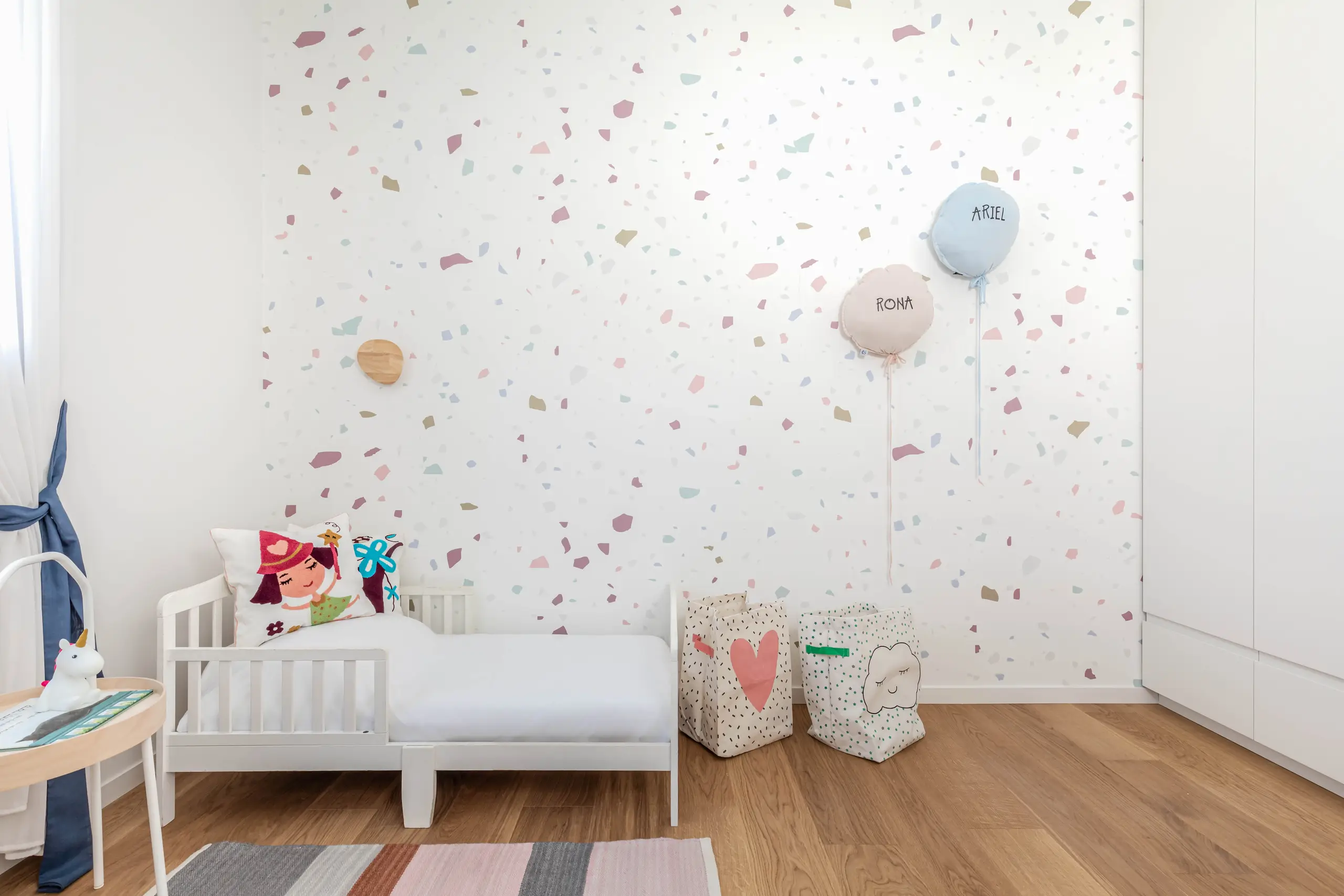 Child's room with a terrazzo-patterned wall, a white bed and a balloon