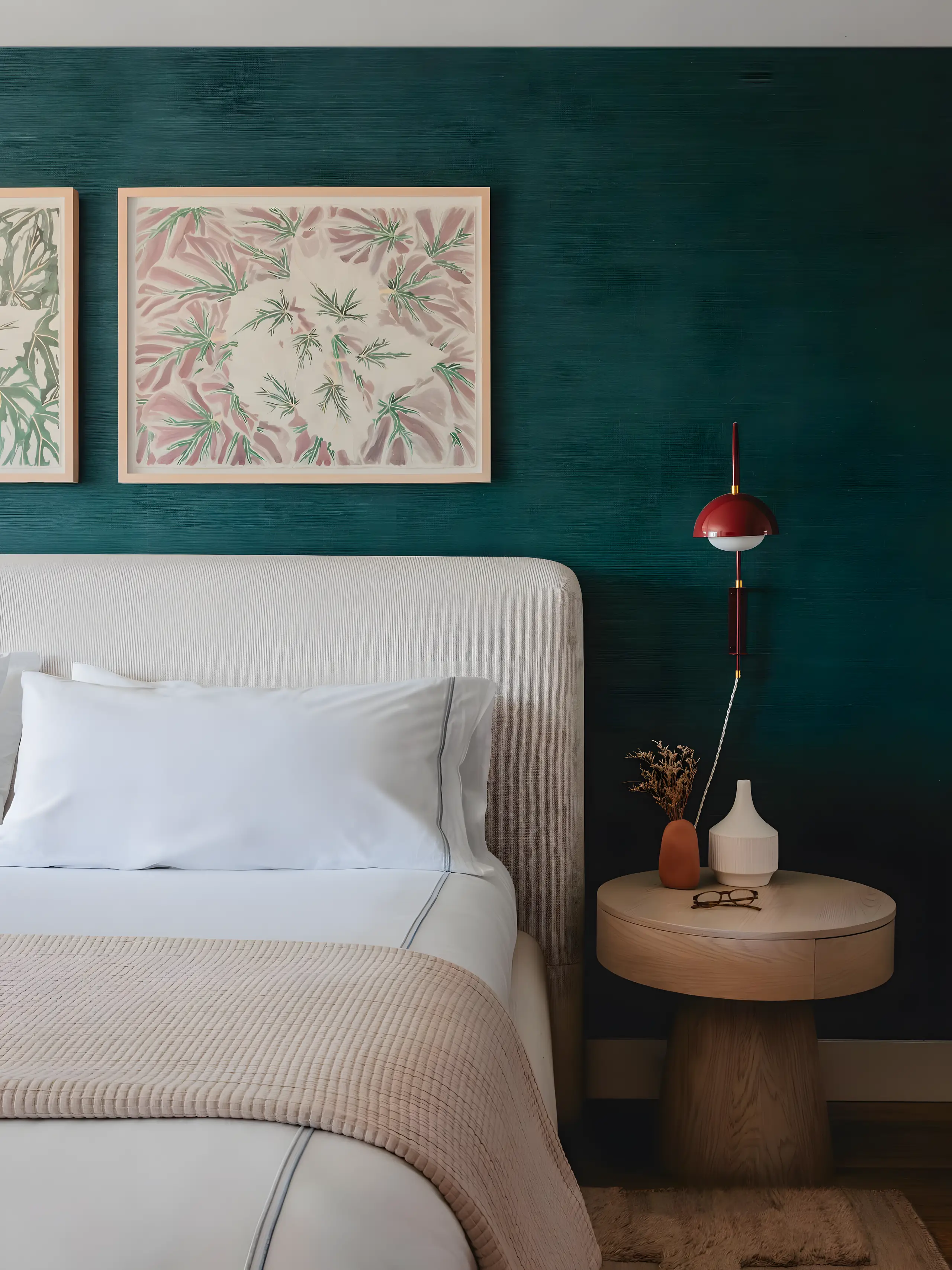 A bedroom on the the north bank: two botanical prints on a deep green grasscloth wall, a red pendant beside the bed